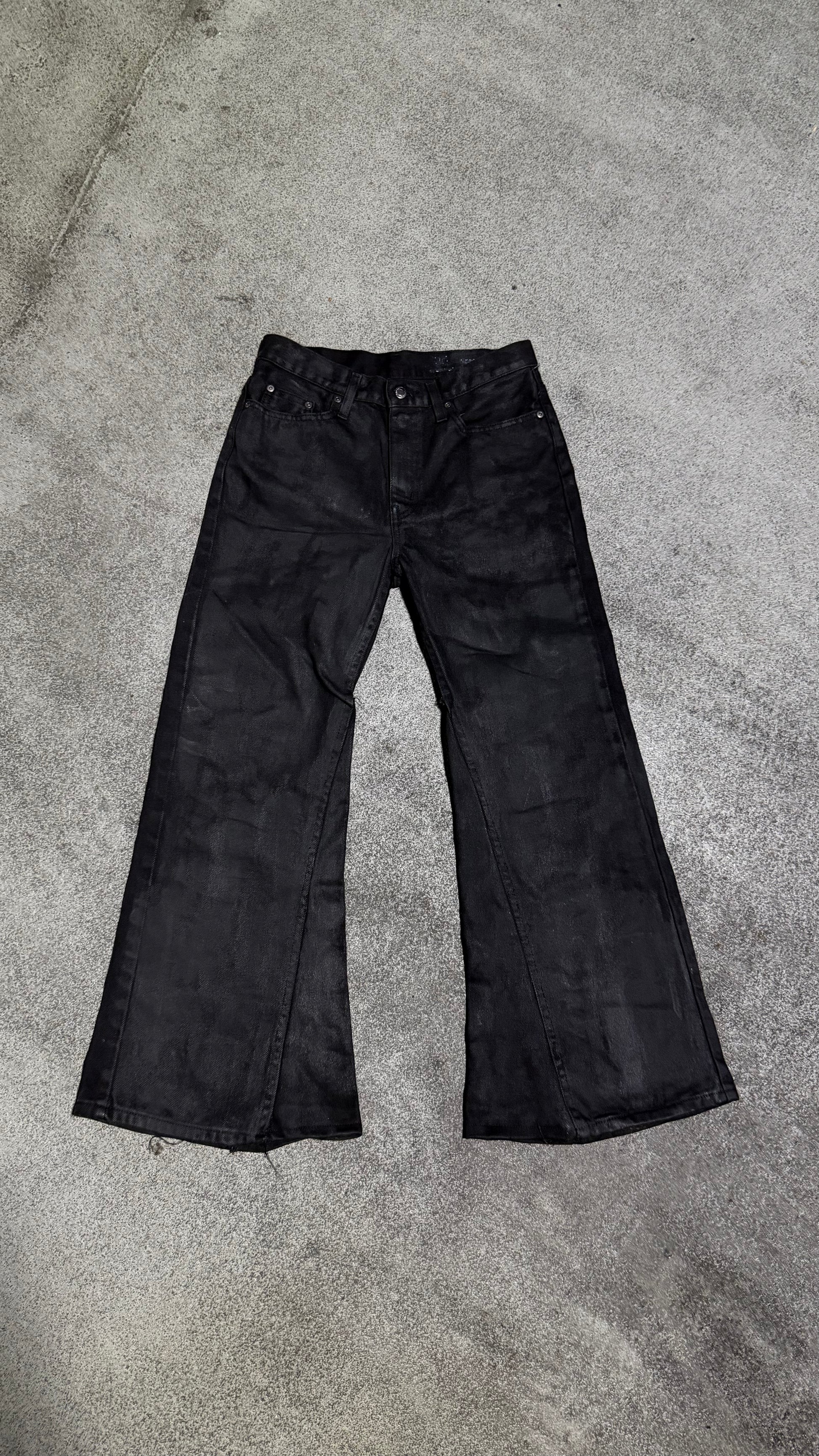 Waxed flared denim jeans by WithoutSaint, showing the fitted waist, flared legs, and textured waxed fabric detail.
