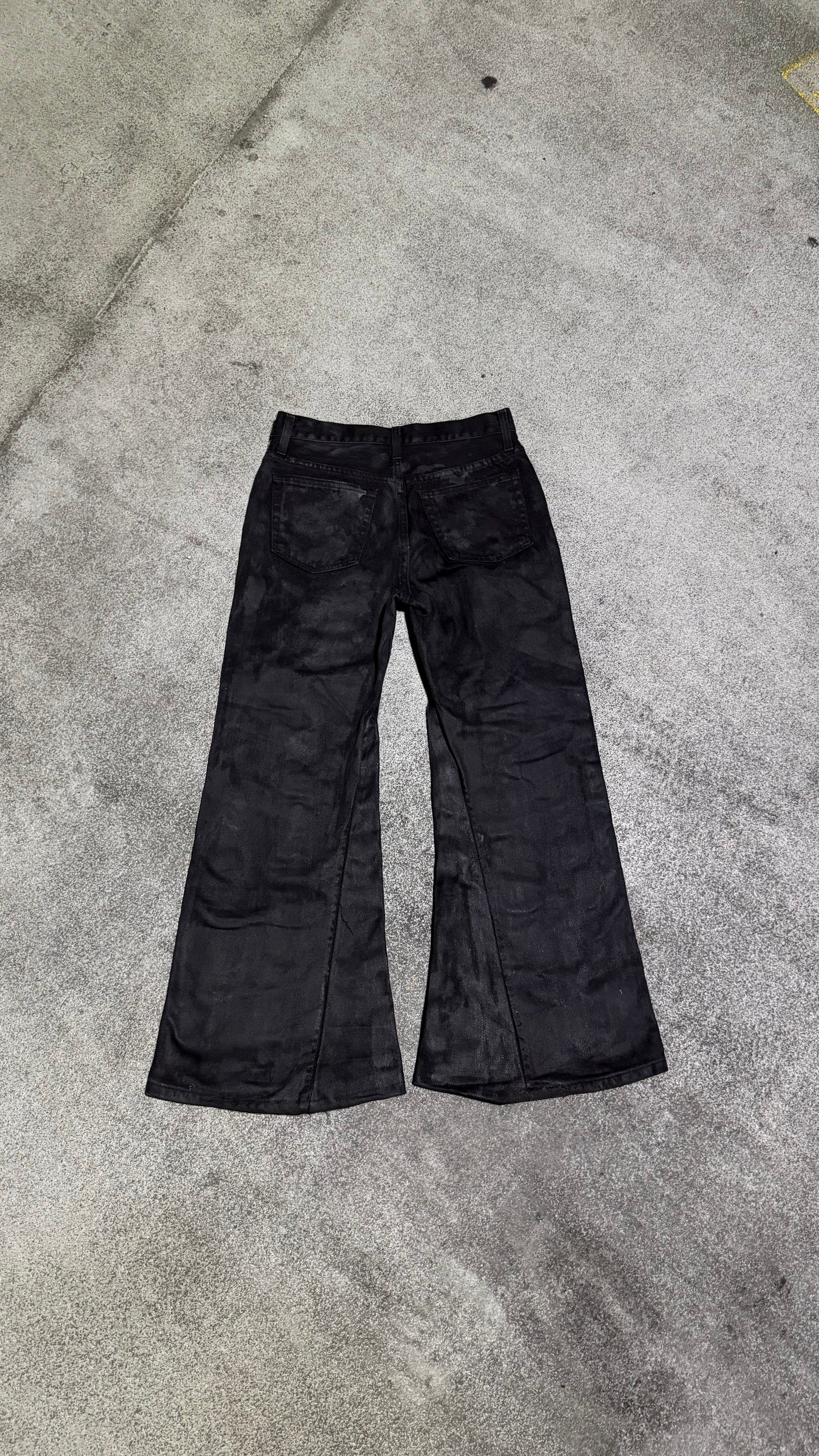 Waxed flared denim jeans by WithoutSaint, showcasing a high-waisted fit and flared leg design with a glossy, waxed finish.